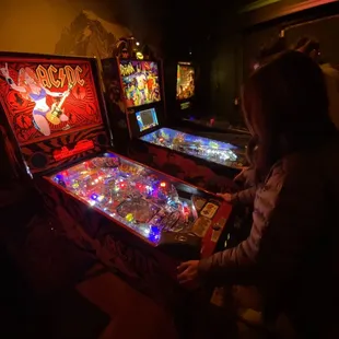 ows a woman playing a pinball game