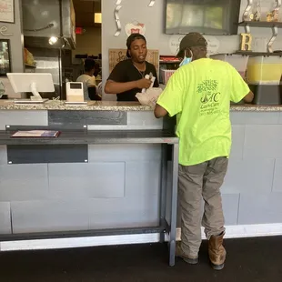 Kind male cashier wraps up customer&apos;s take-out order and offers condiments.
