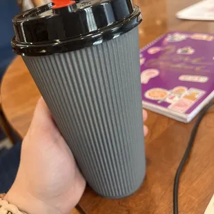 Blue-ish grey colored cup of to-go coffee with cute heart shaped stopper.