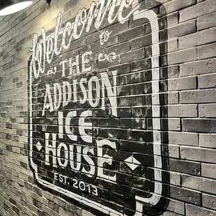a brick wall with a sign that reads welcome to addison ice house