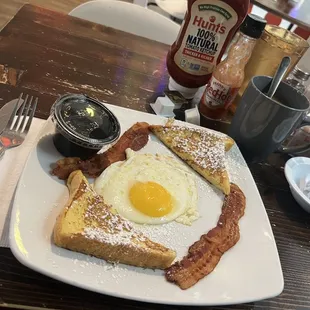 french toast with a sunny side up and bacon