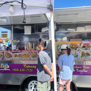 two people standing in front of a food truck