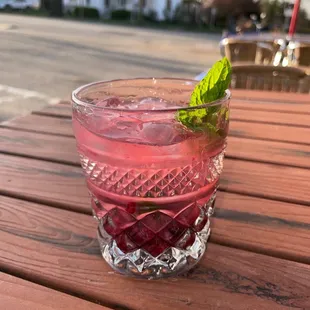 a glass of pink drink on a wooden table