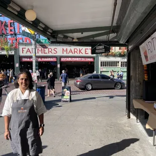 a woman standing in front of a farmers market