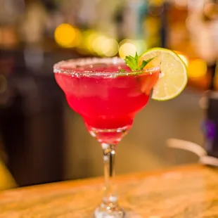 a pink cocktail with lime garnish