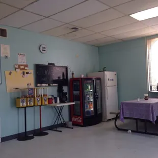 a room with a table, chairs, and a refrigerator