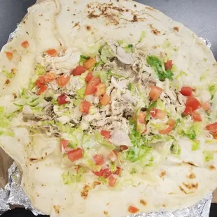 a tortilla with chicken, lettuce and tomatoes