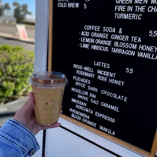 a hand holding a cup of iced coffee