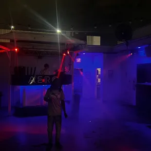 a man standing in front of a bar with red and blue lights