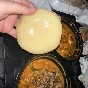 a person placing a piece of bread on top of a bowl of stew