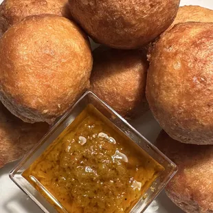 a pile of doughnuts and a bowl of sauce