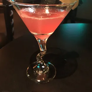 a pink cocktail in a glass with a lemon wedge