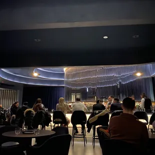 people sitting at tables in a dimly lit restaurant