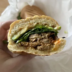 a hand holding a half eaten sandwich