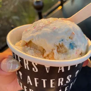 a hand holding a cup of ice cream