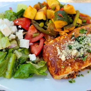 Pastitsio, a traditional pasta dish made with ground beef and bechamel sauce, served with vegetables and salad