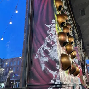 a row of brass bells hanging from a building
