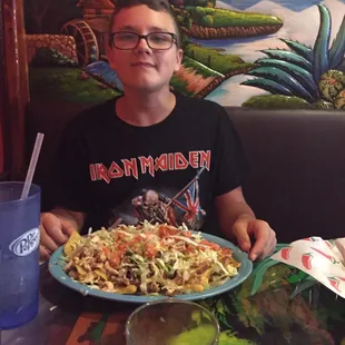 My kid trying to conquer the Nachos Carbon: nachos smothered with shrimp, chicken, steak, grilled veggies, pico, queso and more!