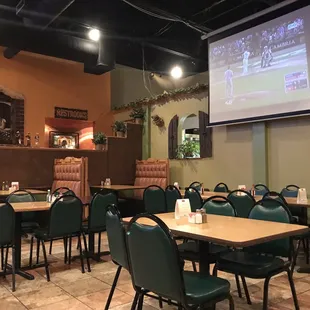 tables and chairs in a restaurant with a projector screen