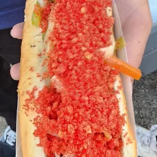 Bacon, hot Cheetos, green, orange peppers, onions, ketchup, mustard, mayo.