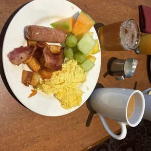 Scrambled eggs, Sausage, fruit, breakfast potatoes, and bacon