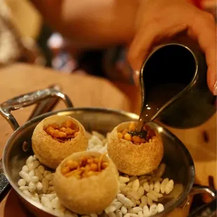 a person pouring a cup of coffee over a plate of food