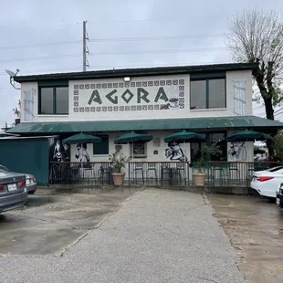 the front of a restaurant with tables and umbrellas