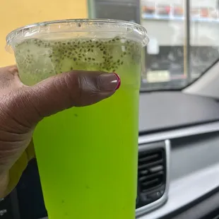 a person&apos;s hand holding a green drink