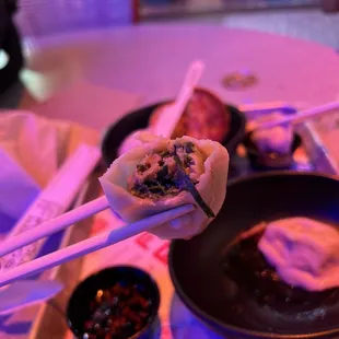 chopsticks holding a dumpling