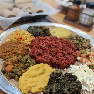 Kifto (spicy raw beef) in the center + collard greens & homemade cheese and veggie combo 2 all on 1 large platter