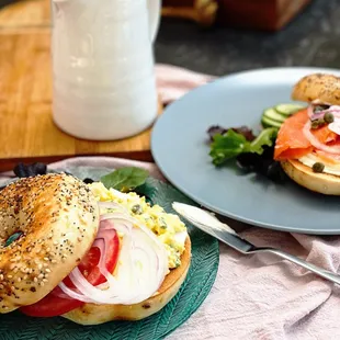 a bagel sandwich on a plate with a cup of coffee