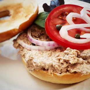 a tuna sandwich with tomatoes and onions