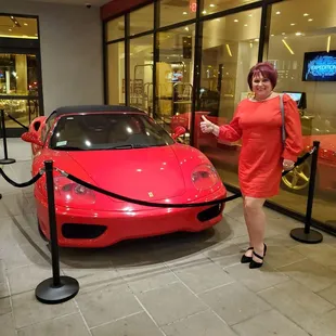 a woman standing next to a red sports car