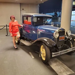a woman standing next to an antique car