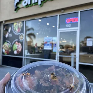 a person holding a plastic container with food inside of it