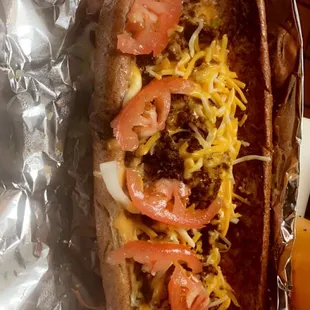 a hot dog covered in cheese and tomatoes