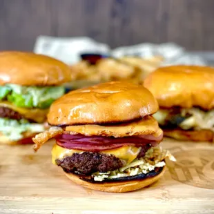 three burgers on a cutting board