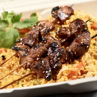 skewered meat and rice in a styrofoam container