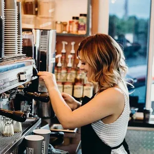 a woman filling a cup of coffee