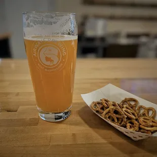 a glass of beer and a basket of pretzels