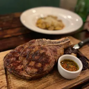 a steak on a cutting board with a side dish
