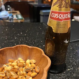 a bowl of nuts and a bottle of beer