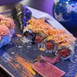 a plate of sushi with meat and vegetables