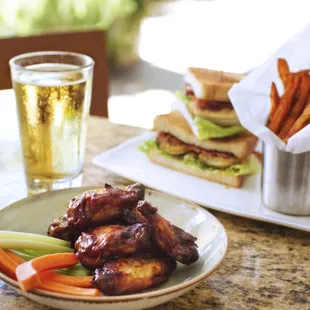 a plate of wings, carrots, and a glass of beer