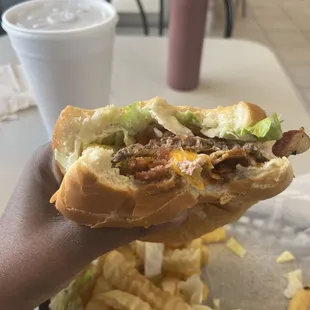 a hand holding a sandwich and fries
