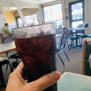 a hand holding a glass of soda