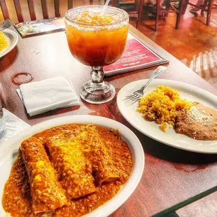 a plate of enchiladas and a glass of orange juice
