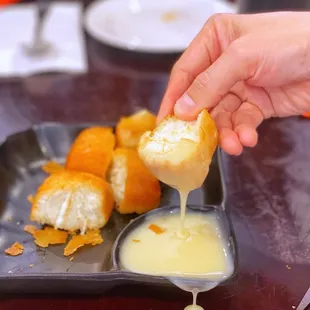 a person dipping a piece of bread into a bowl of butter