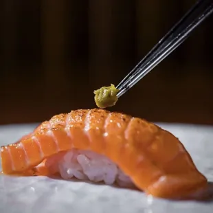 a piece of sushi being held by a pair of chopsticks