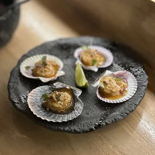 Parmesan Scallops: Hokkaido scallops on the shell, parmesan butter, lime, arare | $18 (4pcs)